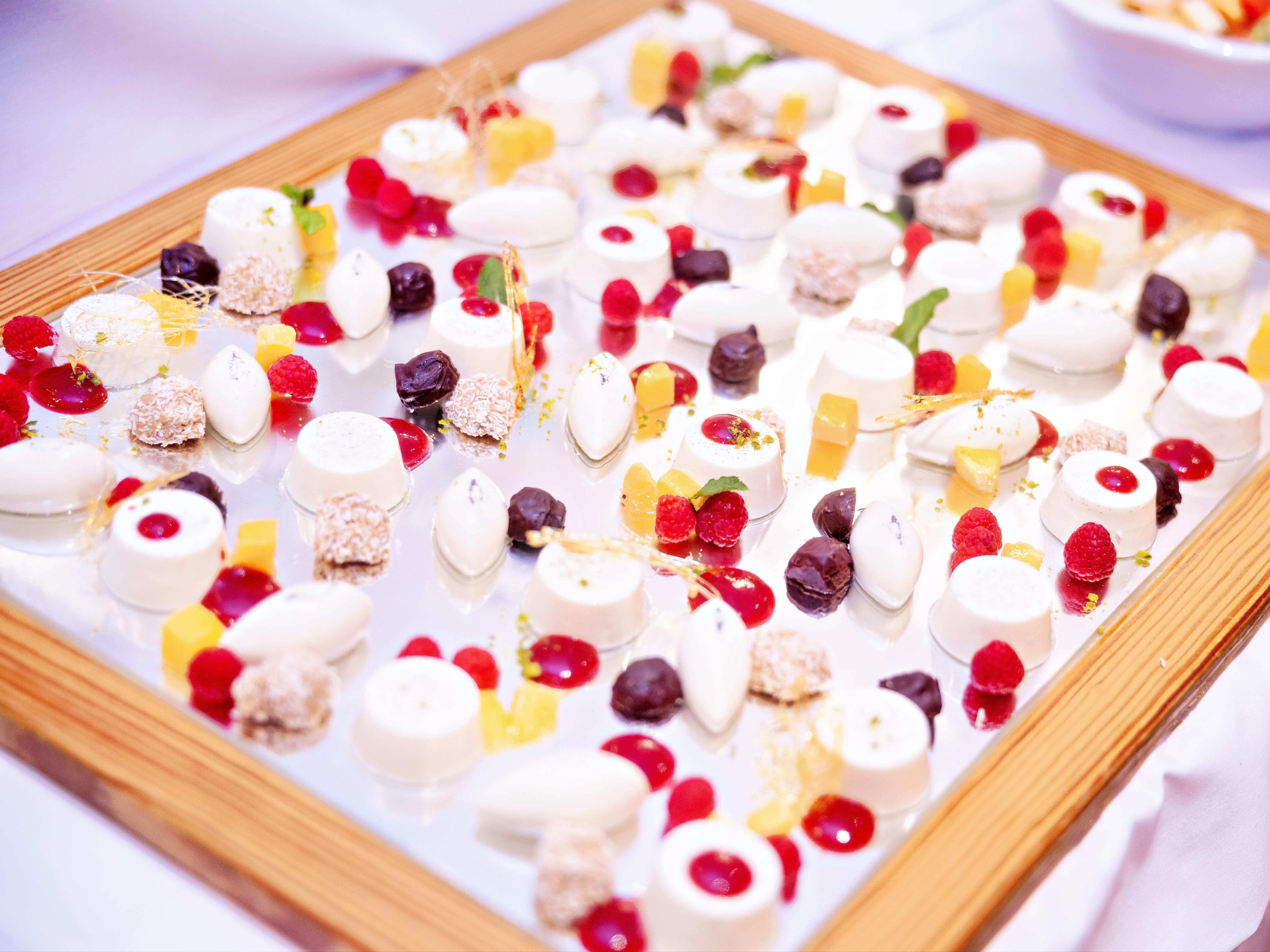 Kleine Panna Cotta Nocken auf einem Spiegel, dekoriert mit rot, gelben Punkten.